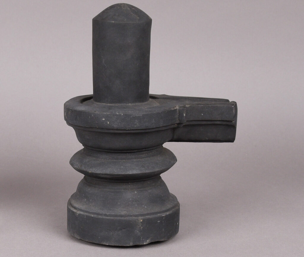 Hinduistisk linga til ære for Shiva, i svart stein. Dreidd base med en oppreist søyle på toppen. Toppen av basen har en utstikkend avsmalning på én side.