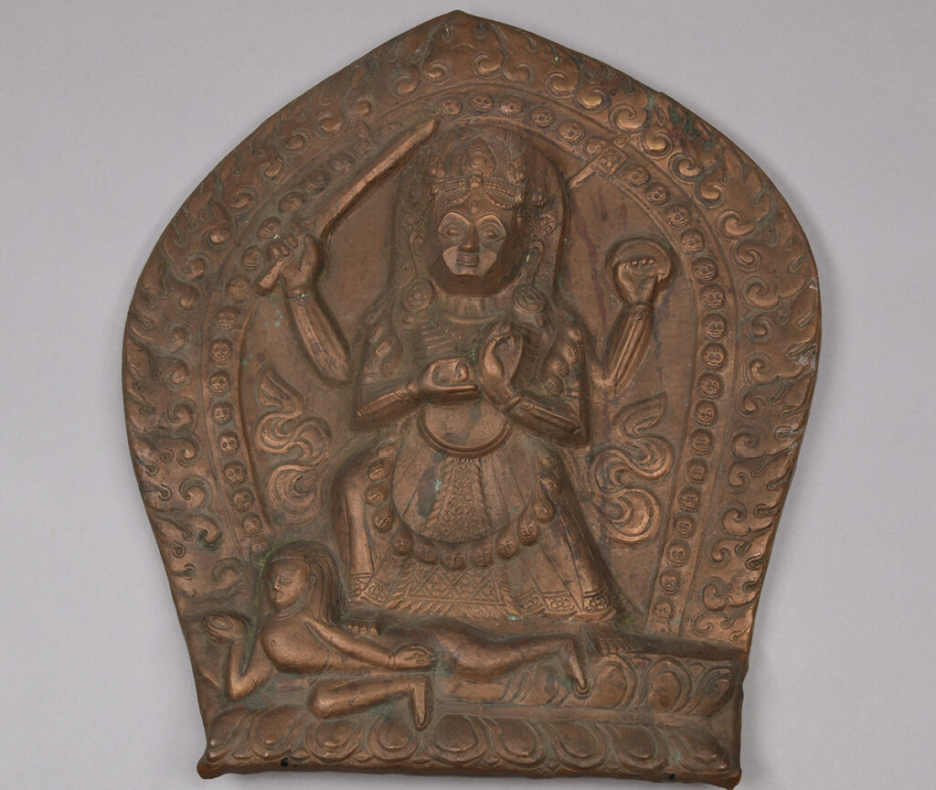 Drevet kobbernblad med motiv av den hinduistiske gudinnen Durga. Gudinnen er fremstilt med fire armer og er omgitt av en bue av hodeskaller.